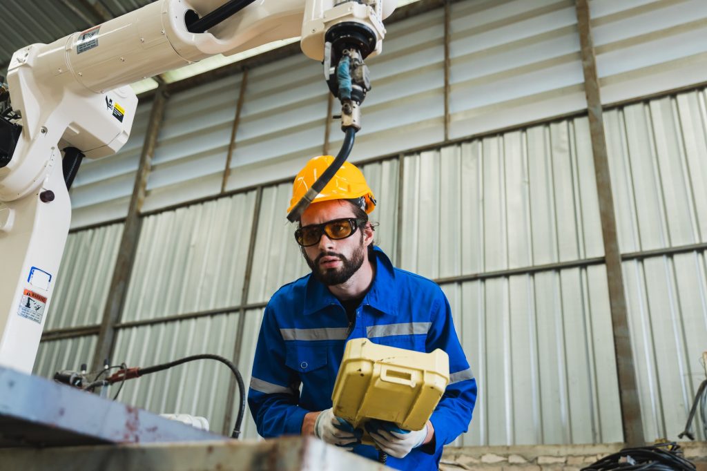 technician maintenance worker or Industrial engineer working and control robotic in heavy industry